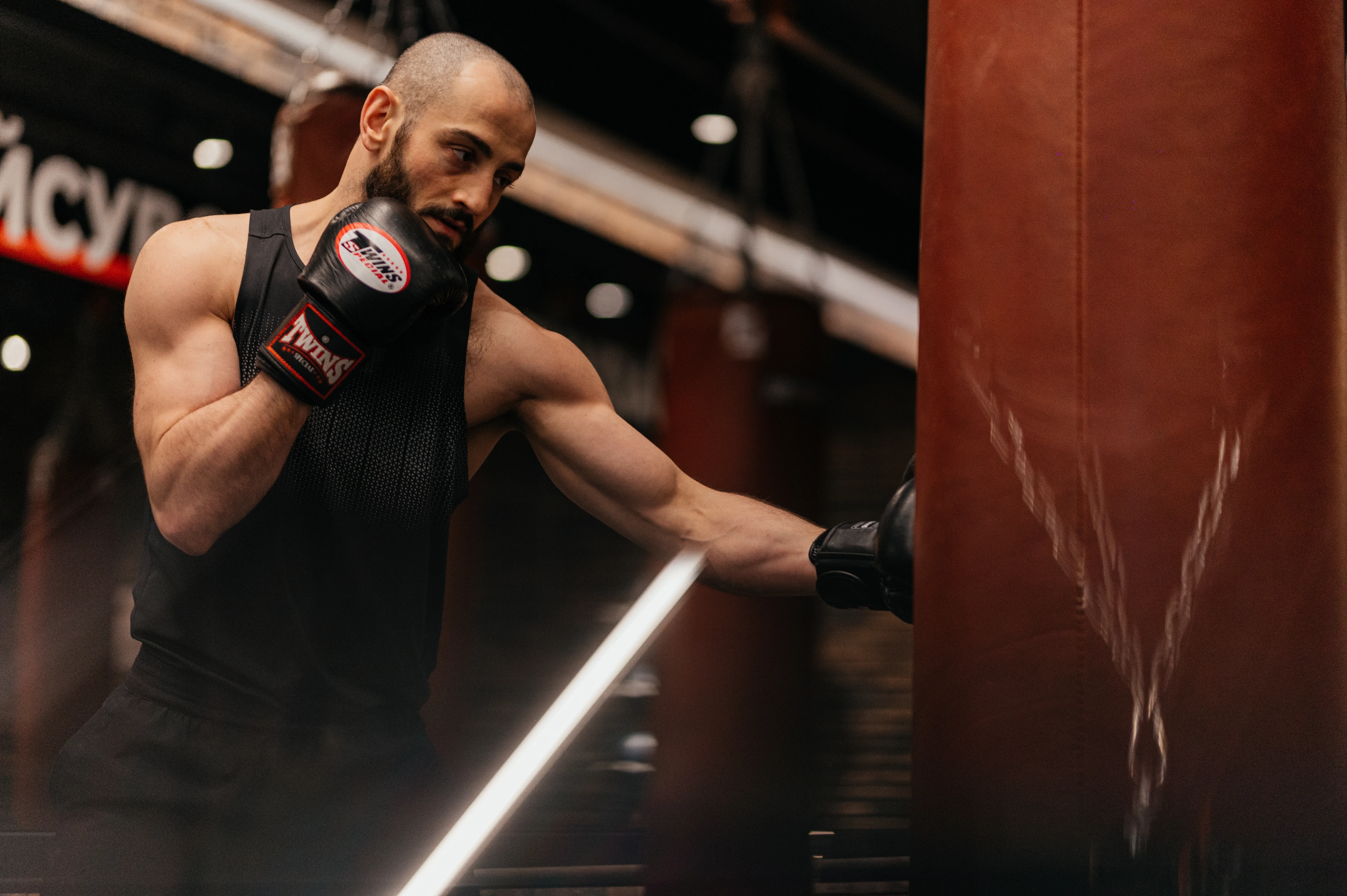 Тренер з боксу тримає лапи під час роботи на лапах зі спортсменом у Synergy Fitness